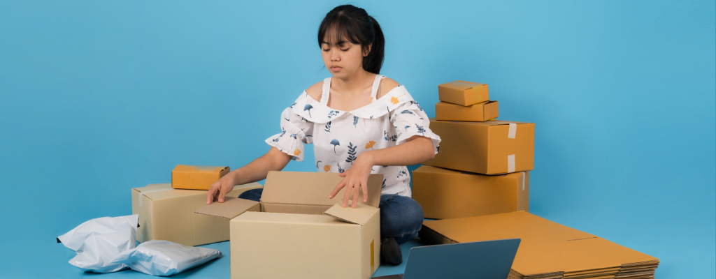 photograph of woman with dark hair sitting on the floor surrounded by shopping bags